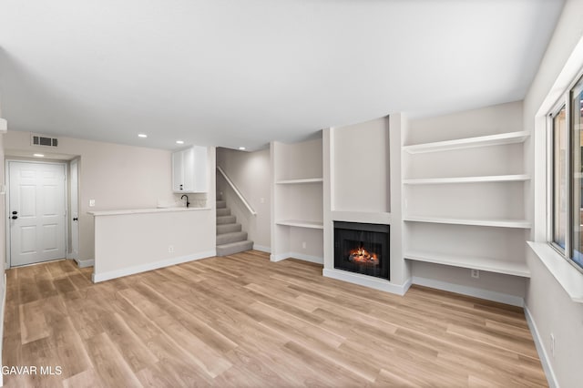 43441 W 30th St Unit 3, Lancaster, CA 93536 - unfurnished living room featuring light wood finished floors, a warm lit fireplace, recessed lighting, and stairway