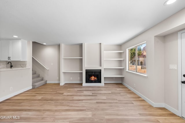43441 W 30th St Unit 3, Lancaster, CA 93536 - unfurnished living room with light wood finished floors, recessed lighting, a lit fireplace, and stairs