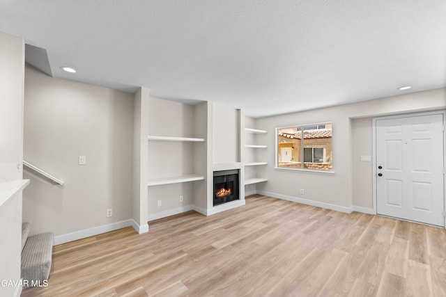 43441 W 30th St Unit 3, Lancaster, CA 93536 - unfurnished living room featuring a warm lit fireplace, light wood finished floors, recessed lighting, and built in shelves