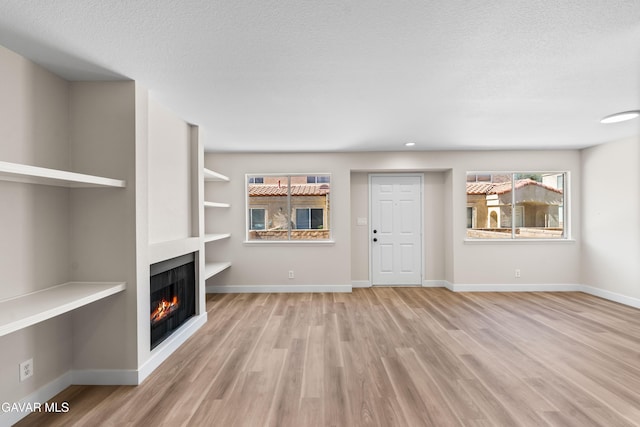 43441 W 30th St Unit 3, Lancaster, CA 93536 - unfurnished living room with a warm lit fireplace, wood finished floors, and a textured ceiling