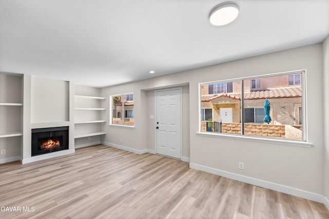 43441 W 30th St Unit 3, Lancaster, CA 93536 - unfurnished living room with a warm lit fireplace, wood finished floors, and built in features