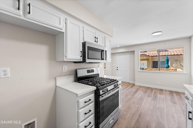 43441 W 30th St Unit 3, Lancaster, CA 93536 - kitchen with appliances with stainless steel finishes, white cabinets, light wood-style flooring, and light stone countertops