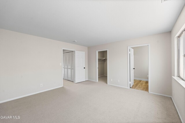43441 W 30th St Unit 3, Lancaster, CA 93536 - unfurnished bedroom with light colored carpet, a walk in closet, a closet, and ensuite bath