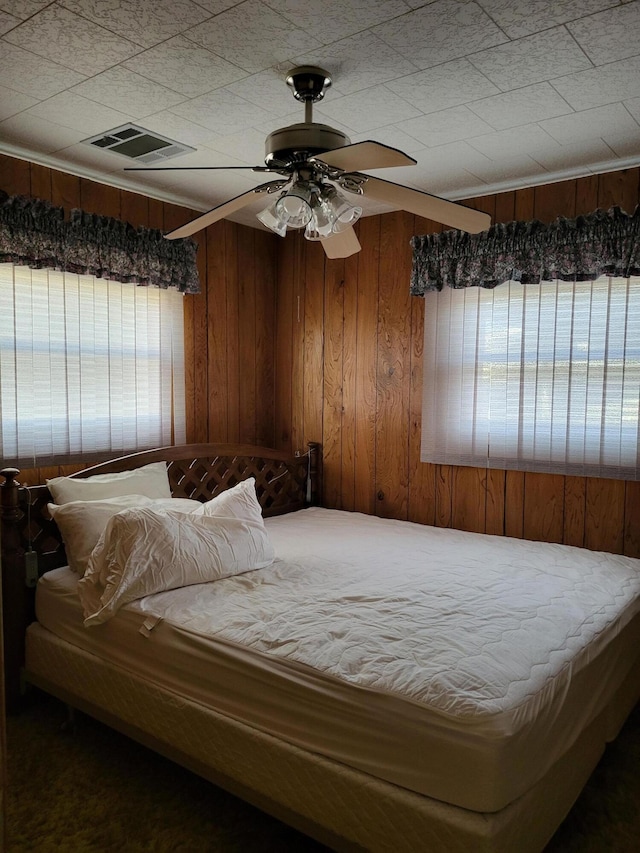 bedroom with wooden walls and ceiling fan