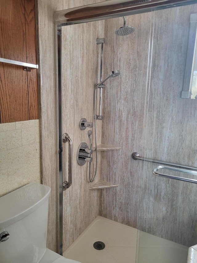 bathroom featuring a shower with shower door and toilet