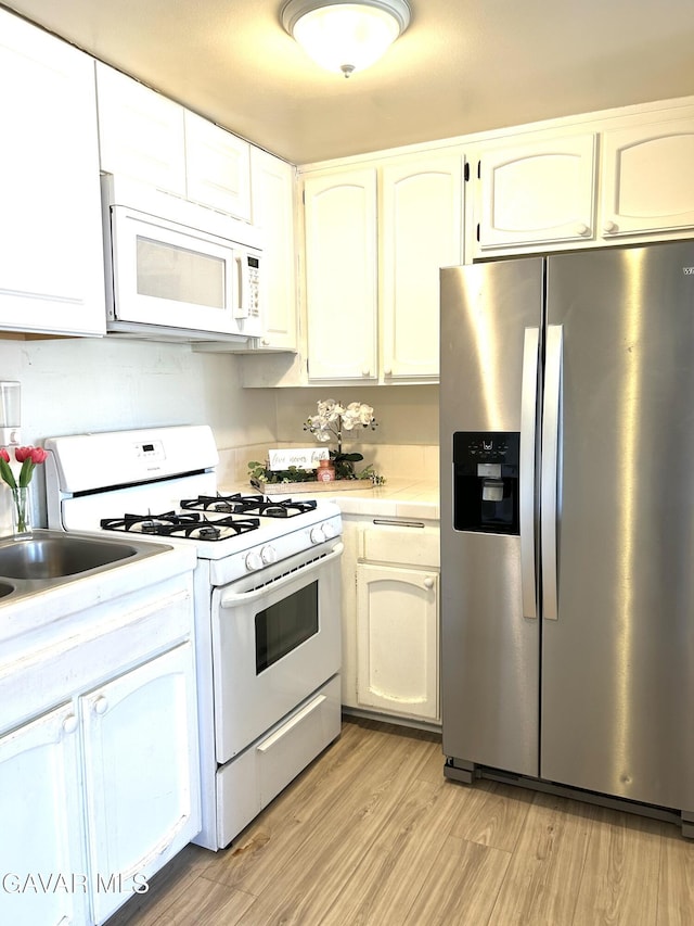 38710 E 10th St Unit 12, Palmdale, CA 93550 - kitchen featuring white appliances, light countertops, light wood-style floors, and white cabinets