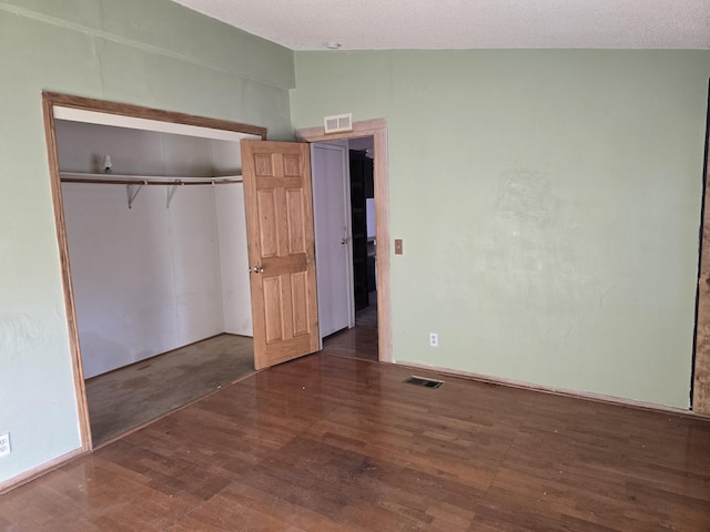 unfurnished bedroom with dark hardwood / wood-style floors, vaulted ceiling, and a closet