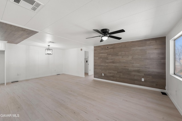 2465 W 55th St, Rosamond, CA 93560 - empty room featuring wood walls, a ceiling fan, light wood-type flooring, a chandelier, and an accent wall