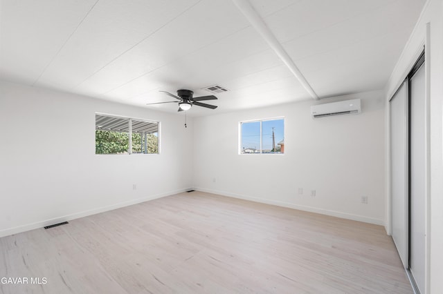 2465 W 55th St, Rosamond, CA 93560 - unfurnished bedroom featuring an AC wall unit, light wood finished floors, ceiling fan, and a closet
