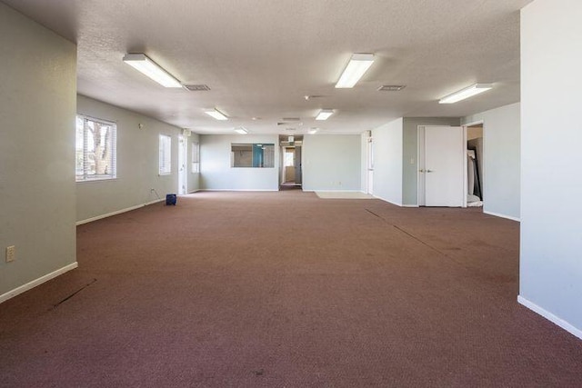 carpeted spare room with a textured ceiling, visible vents, and baseboards