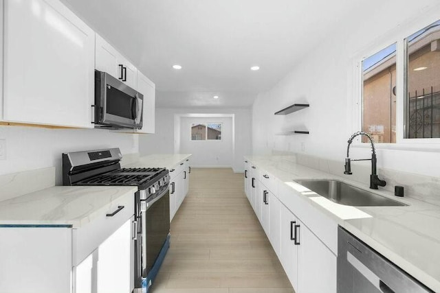 kitchen with light stone counters, sink, white cabinetry, and stainless steel appliances