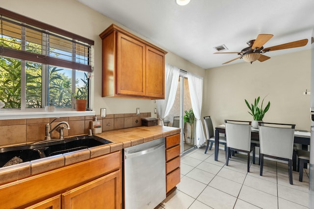 kitchen featuring sink, stainless steel dishwasher, tile counters, ceiling fan, and light tile patterned floors