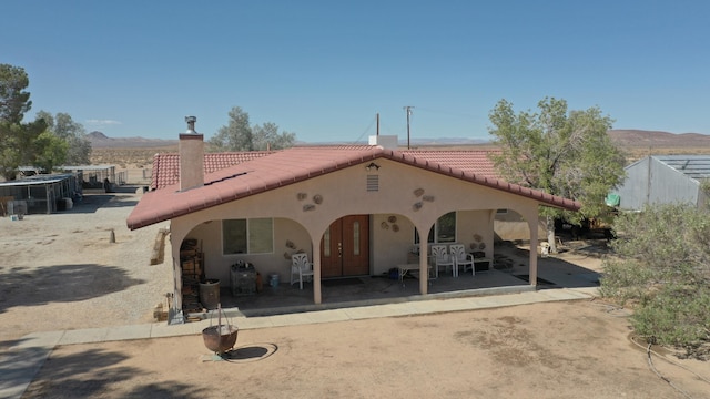 back of property featuring a mountain view and a patio area