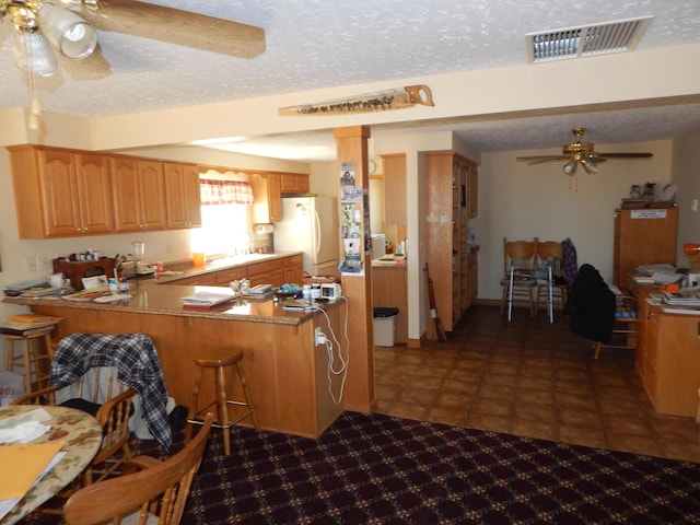 kitchen featuring kitchen peninsula, a textured ceiling, white refrigerator, and ceiling fan