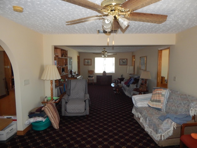 living room featuring carpet flooring, ceiling fan, and a textured ceiling