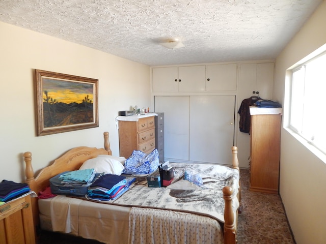 bedroom featuring a textured ceiling, light carpet, and a closet