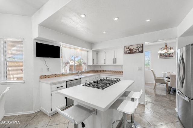 44559 Aspen St, Lancaster, CA 93535 - kitchen with stainless steel appliances, white cabinets, a chandelier, light countertops, and light tile patterned flooring