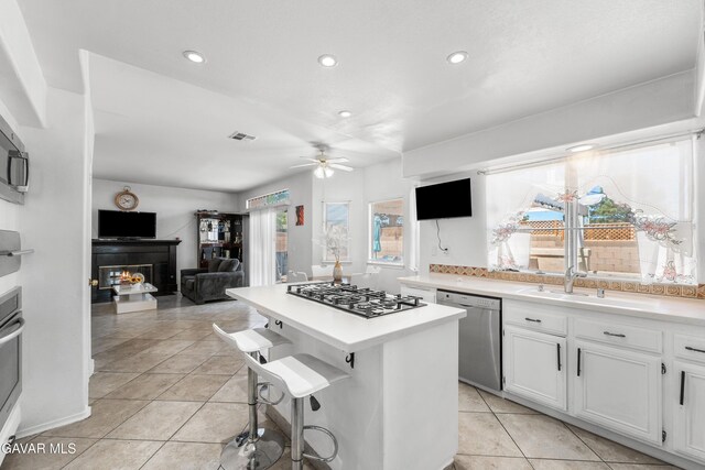 44559 Aspen St, Lancaster, CA 93535 - kitchen with stainless steel appliances, a warm lit fireplace, recessed lighting, a ceiling fan, and a kitchen island