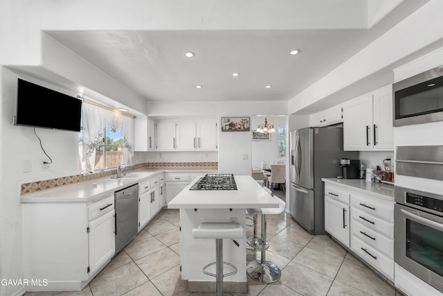 44559 Aspen St, Lancaster, CA 93535 - kitchen featuring stainless steel appliances, a center island, white cabinetry, light countertops, and a breakfast bar area