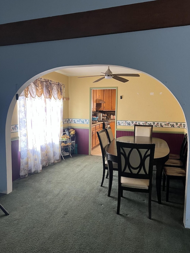 dining space with carpet floors, arched walkways, and a ceiling fan