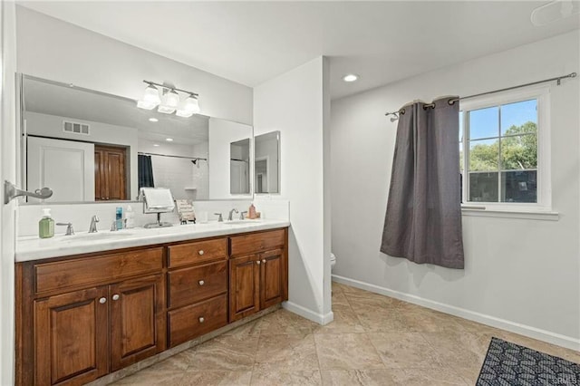 bathroom with toilet, a sink, baseboards, and double vanity