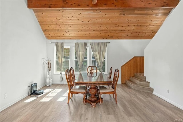 dining room featuring lofted ceiling with beams, stairway, and light wood finished floors