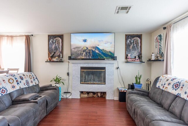 living room featuring visible vents, a tiled fireplace, and wood finished floors
