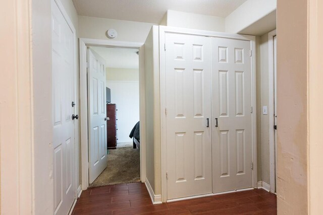 corridor featuring baseboards and dark wood-type flooring