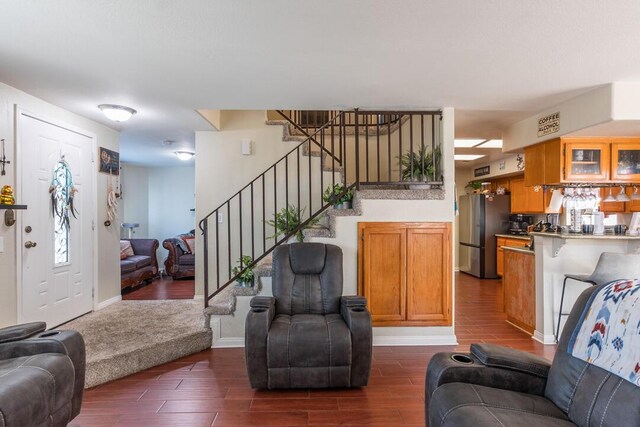 living area with baseboards, stairs, and dark wood-style floors