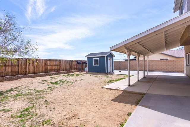 view of yard featuring a patio area, a fenced backyard, an outdoor structure, and a storage shed
