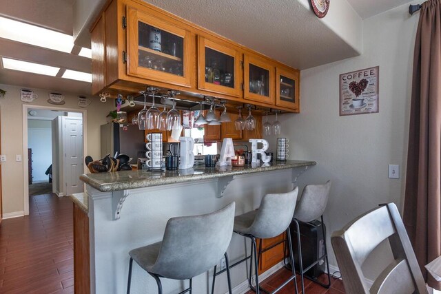 bar featuring freestanding refrigerator, dark wood-type flooring, and baseboards
