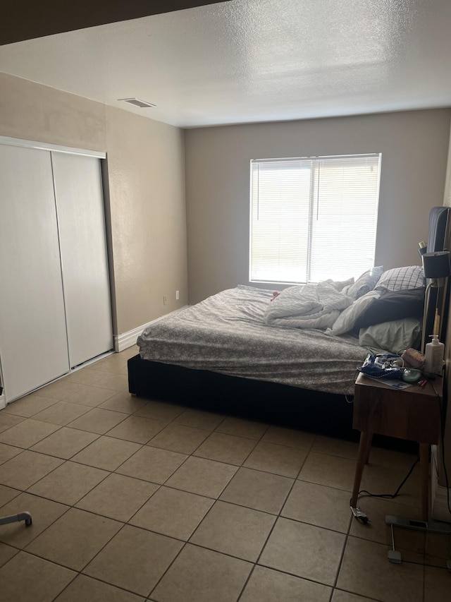 bedroom with a closet, light tile patterned floors, and a textured ceiling
