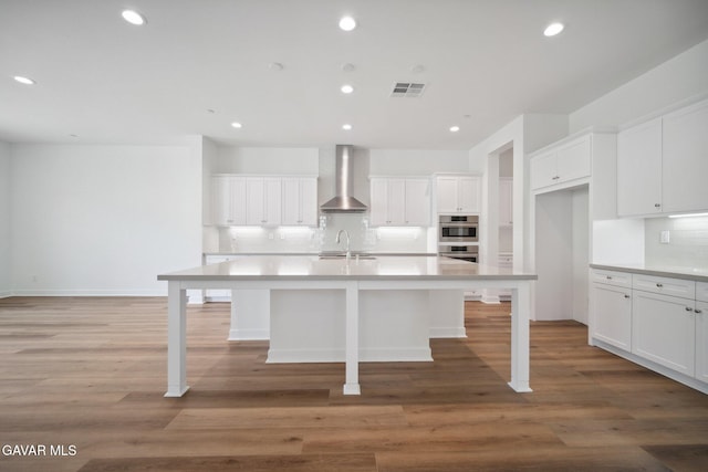 3716 Eliopulos Ranch Dr, Palmdale, CA 93551 - kitchen featuring wall chimney range hood, decorative backsplash, white cabinetry, an island with sink, and recessed lighting