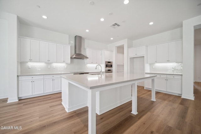3716 Eliopulos Ranch Dr, Palmdale, CA 93551 - kitchen featuring wall chimney range hood, decorative backsplash, white cabinets, an island with sink, and recessed lighting
