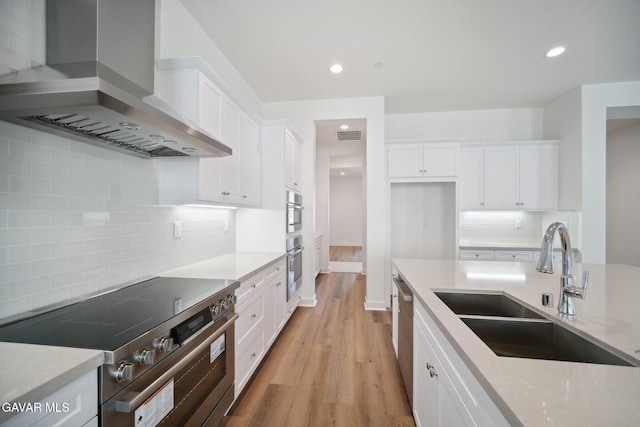 3716 Eliopulos Ranch Dr, Palmdale, CA 93551 - kitchen featuring wall chimney exhaust hood, appliances with stainless steel finishes, white cabinets, decorative backsplash, and recessed lighting