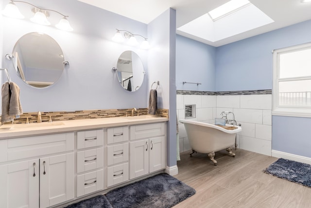 36755 Tierra Subida Ave, Palmdale, CA 93551 - bathroom featuring tile walls, a skylight, double vanity, a freestanding bath, and wood finished floors