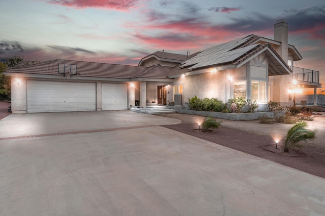 36755 Tierra Subida Ave, Palmdale, CA 93551 - view of front of house featuring concrete driveway, a garage, a chimney, stucco siding, and roof mounted solar panels