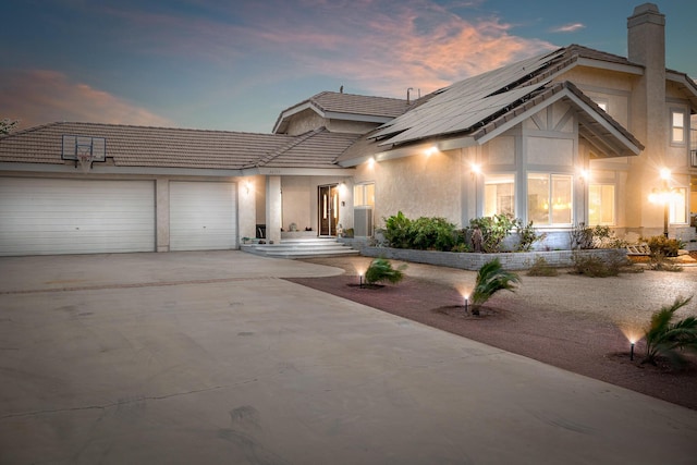 36755 Tierra Subida Ave, Palmdale, CA 93551 - view of front facade with a garage, stucco siding, concrete driveway, roof mounted solar panels, and a chimney