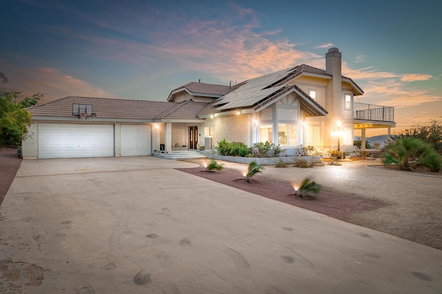 36755 Tierra Subida Ave, Palmdale, CA 93551 - view of front facade with a balcony, an attached garage, a chimney, roof mounted solar panels, and concrete driveway