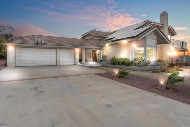 36755 Tierra Subida Ave, Palmdale, CA 93551 - view of front facade featuring a chimney, driveway, an attached garage, roof mounted solar panels, and stucco siding