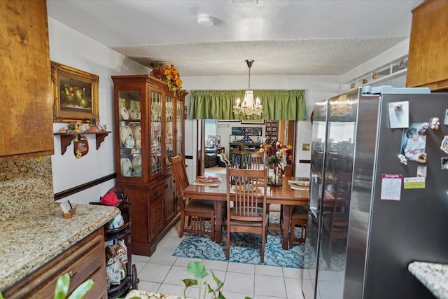 dining room with light tile patterned floors, a notable chandelier, and a textured ceiling