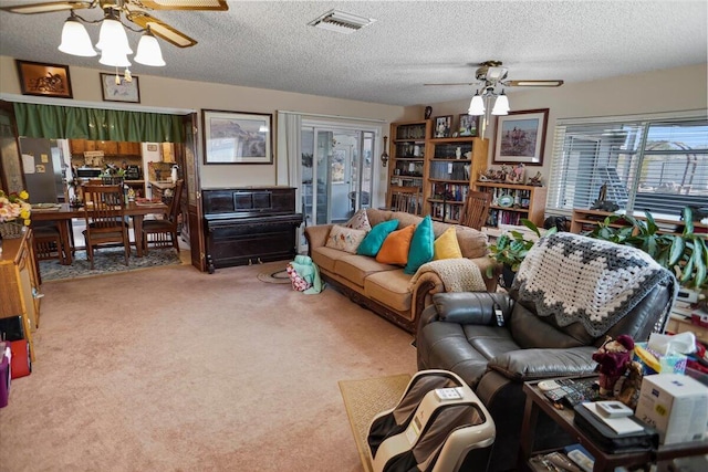 living room with visible vents, carpet, ceiling fan, and a textured ceiling