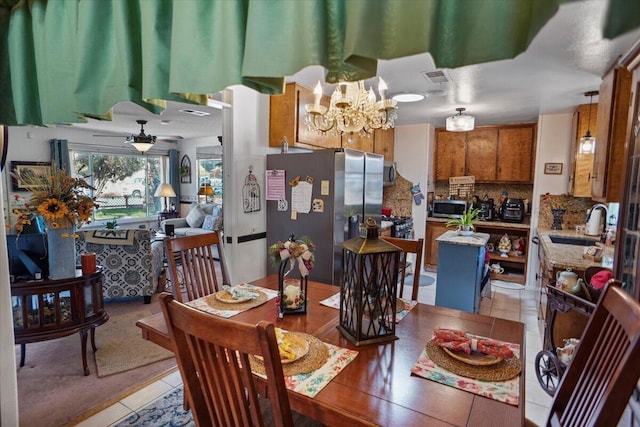 dining area featuring light tile patterned flooring, ceiling fan with notable chandelier, and visible vents