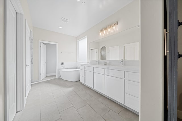 bathroom with a tub to relax in, vanity, and tile patterned flooring