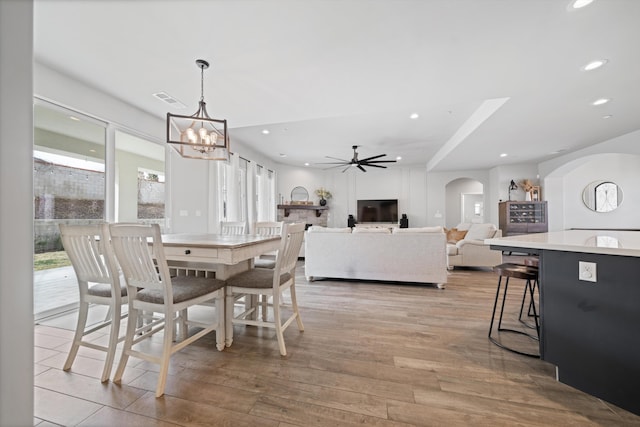 dining area with ceiling fan with notable chandelier and light wood-type flooring