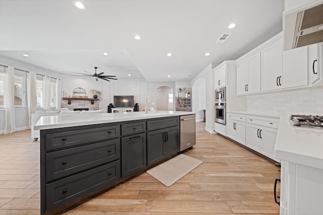 kitchen featuring extractor fan, appliances with stainless steel finishes, sink, white cabinets, and a center island