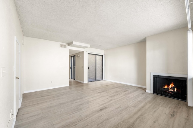 unfurnished living room with a textured ceiling and light wood-type flooring