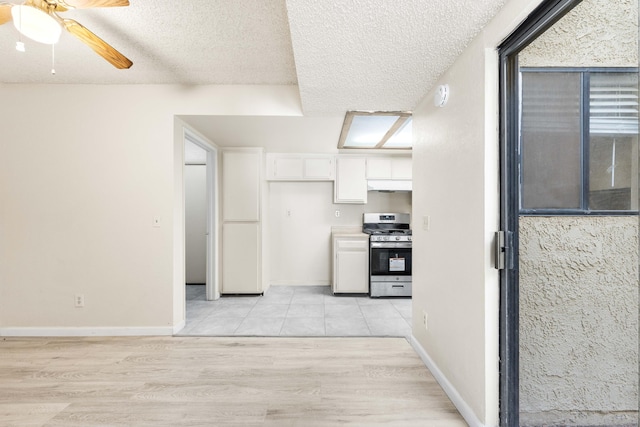 kitchen featuring stainless steel range with gas cooktop, light wood-type flooring, white cabinets, and a textured ceiling