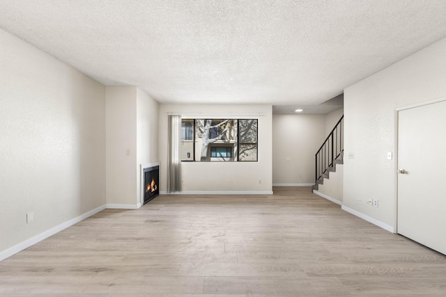 unfurnished living room featuring light hardwood / wood-style floors and a textured ceiling