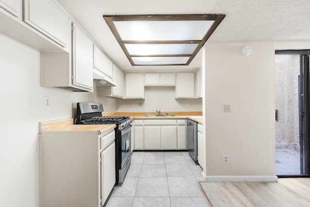 kitchen with light tile patterned flooring, sink, a textured ceiling, stainless steel appliances, and white cabinets